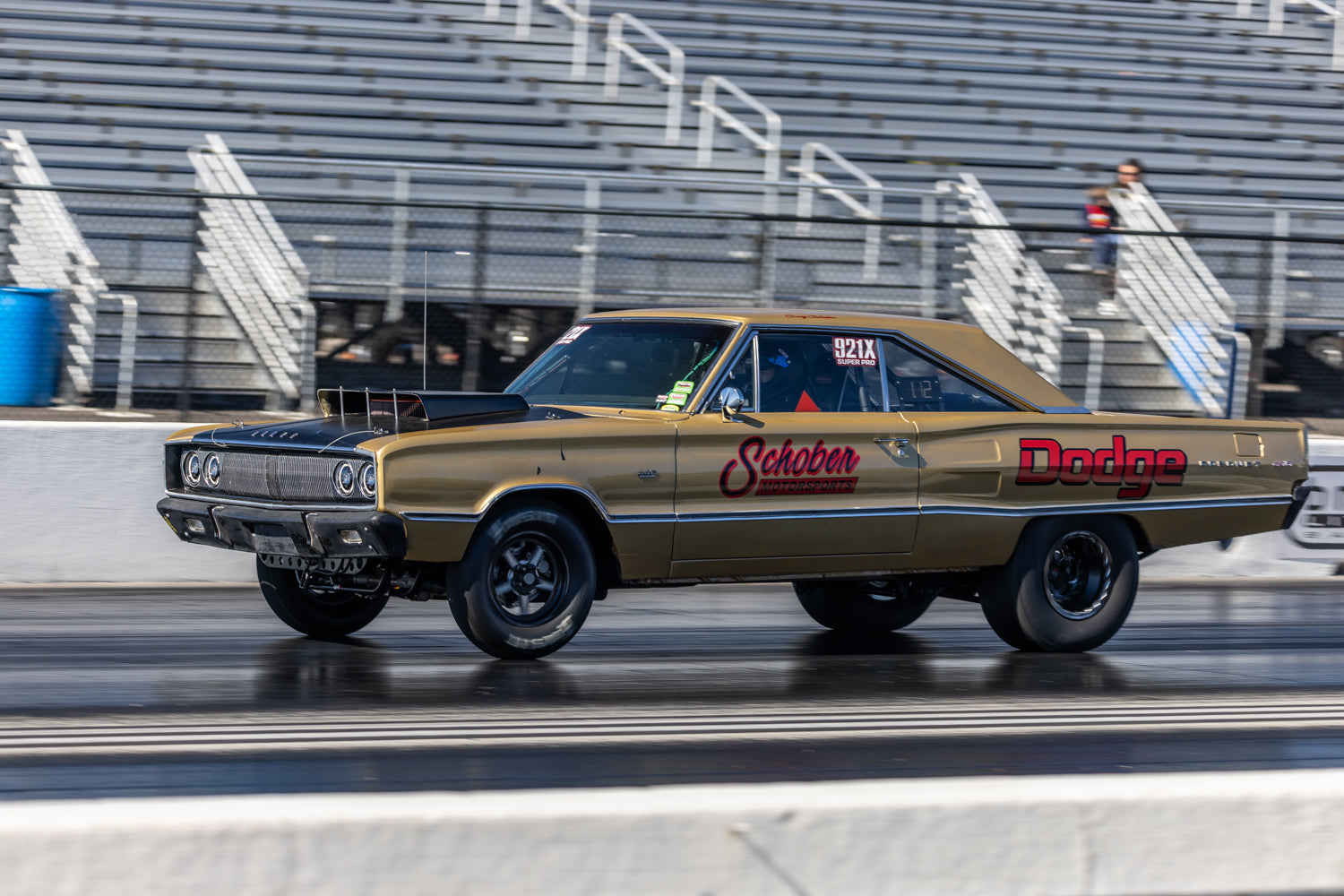 Gold and black Dodge vehicle on a racetrack with 'Schober Motorsports.com' branding.